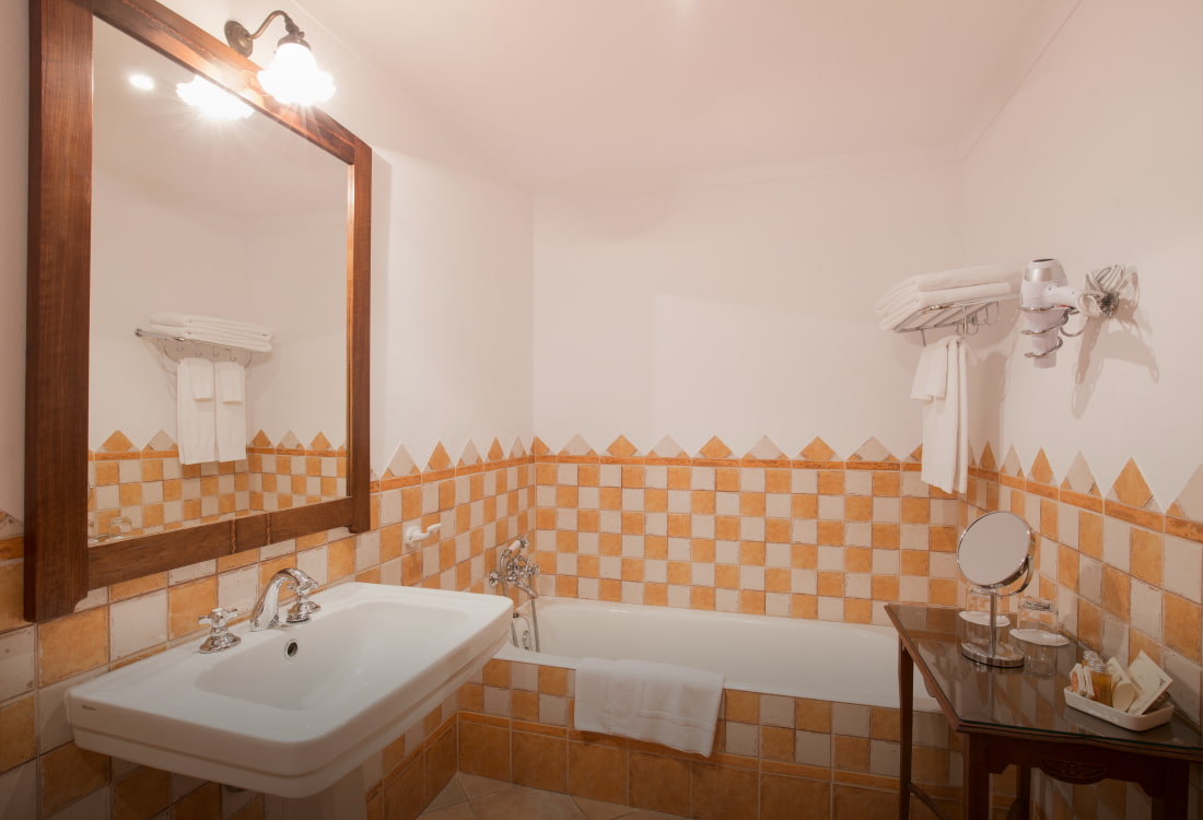 Baño alicatado con baldosas blancas y naranjas, con bañera y lavabo